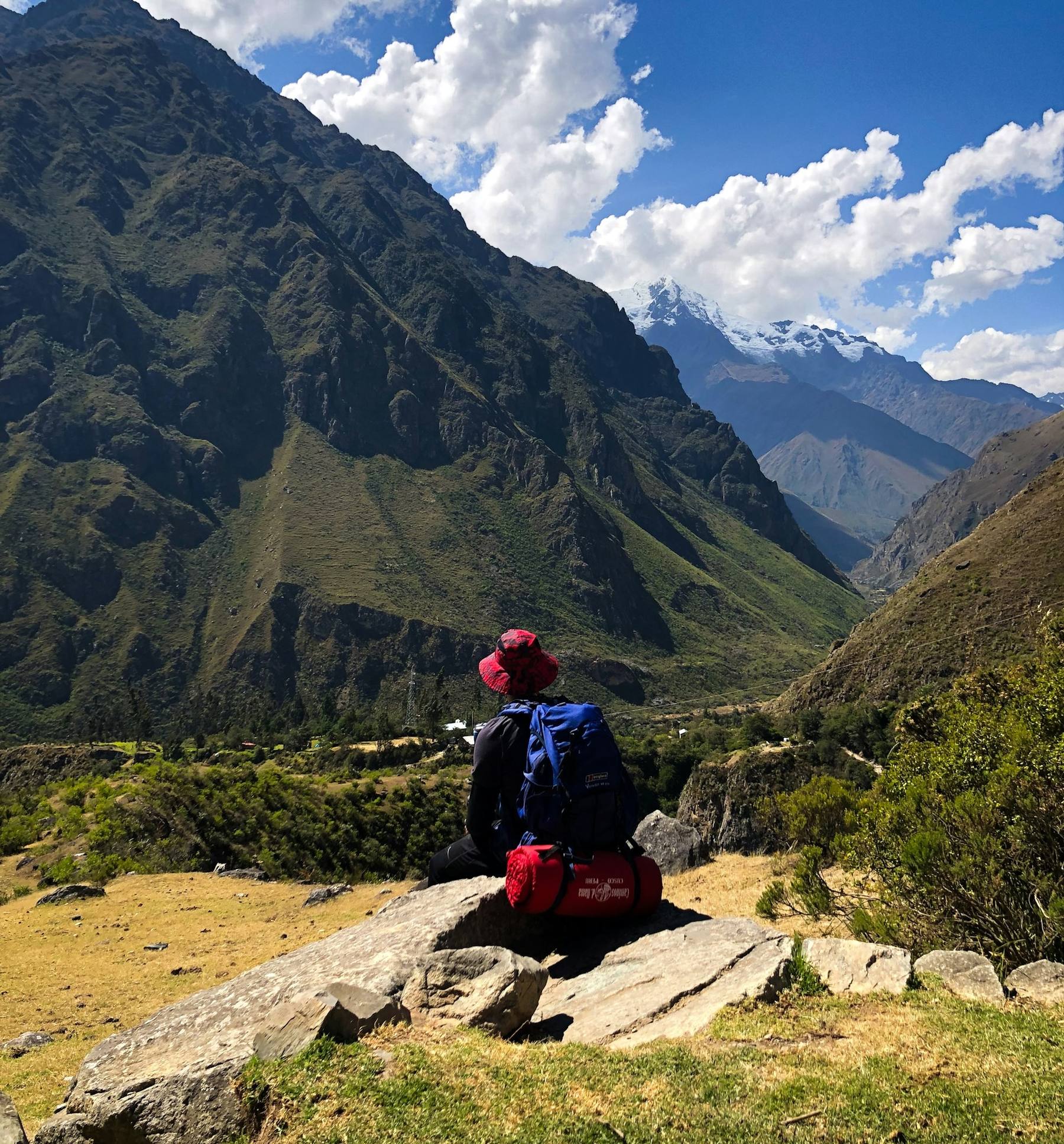 A line of trekkers ascending stone steps on the Inca Trail with cloud-covered Andean peaks behind them