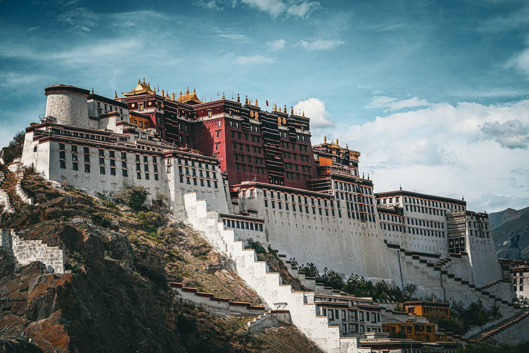 The north face of Everest rising behind Rongbuk Monastery at the head of the valley, the Friendship Highway threading the high brown plateau toward base camp